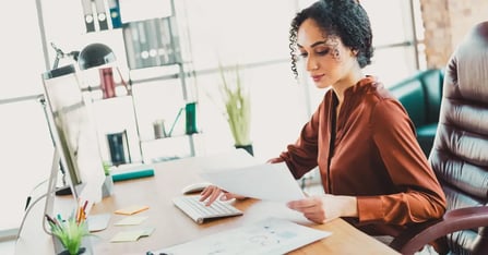 Female Executive Assistant sitting at her desk working productively after completing a desk setup